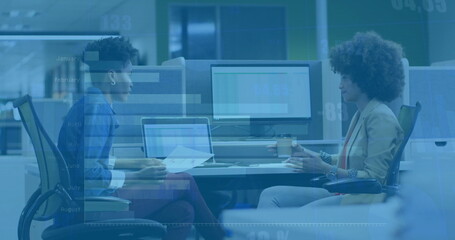 Image of diagrams and data processing over biracial female colleagues talking in office