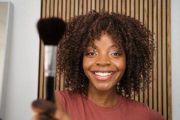 Young woman holding a makeup brush and smiling