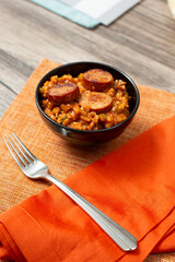 A view of a small bowl of jambalaya, topped with slices of kielbasa sausage.