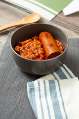 A view of a bowl of jambalaya soup, featuring large sausage chunk.