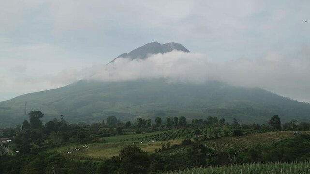 Mount Sinabung surrounded by clouds, creating a mystical and breathtaking volcanic landscape. Perfect for nature and travel projects.