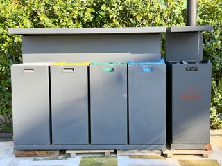 Outdoor Recycling Bins in Sunlight. Outdoor recycling bins in sunlight against greenery. Perfect for eco-friendly themes, environmental campaigns, or garden settings.