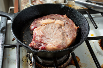 A view of a ribeye steak in a cast iron skillet.
