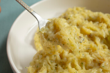 A closeup view of a fork scooping some spaghetti squash Alfredo.