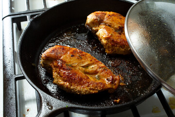 A view of some tequila lime chicken breasts frying in a cast iron skillet.