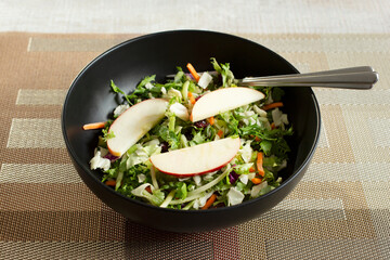 A view of a salad, topped with apples and cranberries.