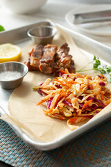 A view of a side of BBQ coleslaw next to a pile of sliced streak strips.
