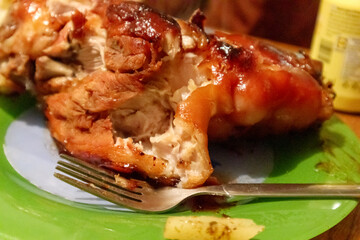 
an oven-baked pork leg with crispy skin on a plate, and a fork shot into a slice of potato.