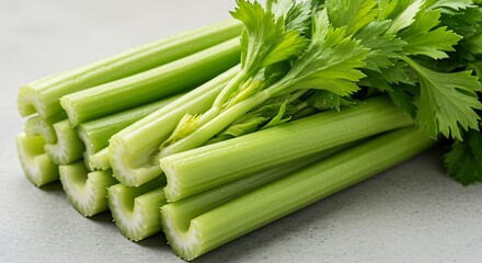 A bunch of fresh, light green celery stalks with crisp leaves on top.