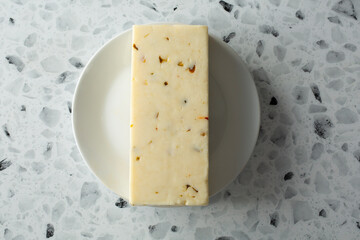 A top down view of a block of pepper jack cheese, on a plate.
