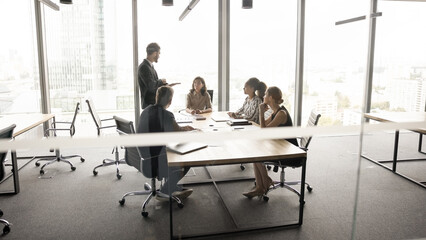Businesspeople negotiate in office, gathered around conference table, engaged in formal discussion...