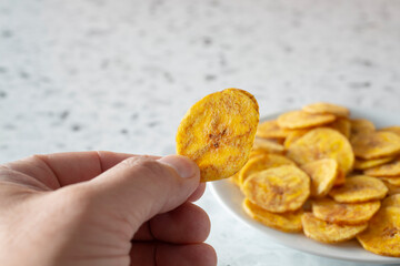A view of a hand holding a plantain chip. © DAVID