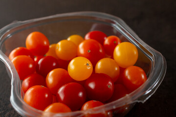 A closeup view of a plastic container of teeny tiny tomatoes.