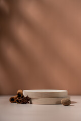 Wooden round podium product showcase on brown background with spices cinnamon, nutmeg and star anise. Aromatic perfumed cosmetic background