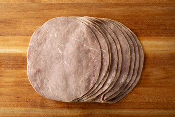 A top down view of slices of roast beef, on a wood board.