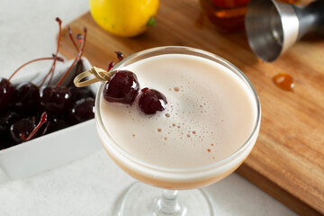 A view of a cocktail with some Amarena cherries as garnish.