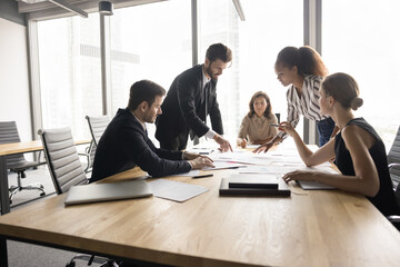 Strategic project evaluation meeting. Group of multiethnic businesspeople, marketing experts take part in briefing, review documents related to upcoming project, share ideas, researching, forecasting