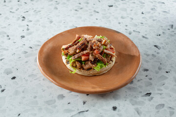 A view of a carnitas sope, on a plate.