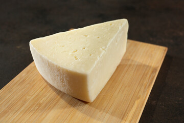 A view of a block of fontina cheese, on a wood board.