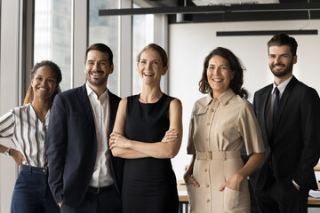 Obraz premium Diverse corporate members, executives, managers represent company posing at workplace. Five multiracial businesspeople standing together in office, exuding professionalism, unity and business success