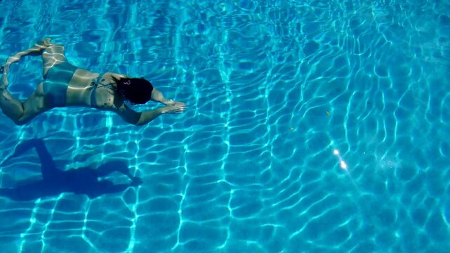 Woman Diving Through a Blue Pool on a Sunny Day