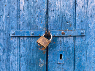 Old lock on a blue weathered wooden door