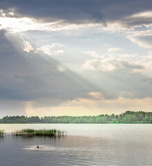 Lake with a cloudy sky and a person swimming in the water