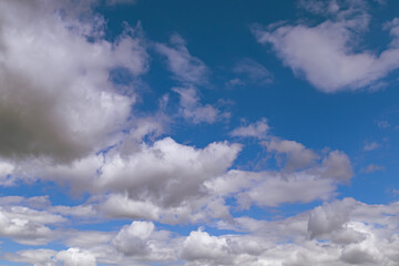 Scattered white clouds against a bright blue sky on a sunny day