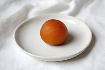 A single, golden-brown Gulab Jamun rests on a pristine white plate.