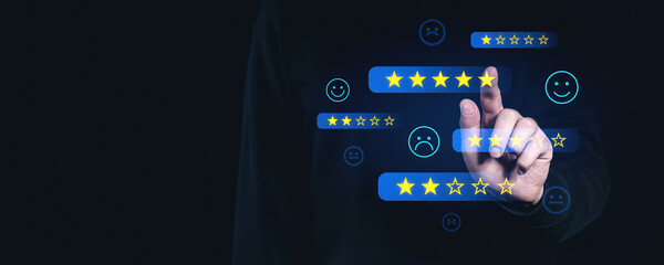 Finger selecting star rating on virtual screen interface with emojis on dark background. Concept of online reviews, feedback, and performance evaluation.