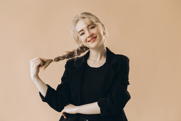 Smiling Woman Posing Confidently in a Black Suit Against a Neutral Background