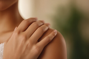 Close-up of a woman's hand resting on her shoulder, concept of self-care and relaxation