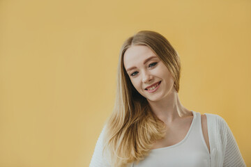 Smiling Young Woman Posing Against a Vibrant Yellow Background in Casual Attire