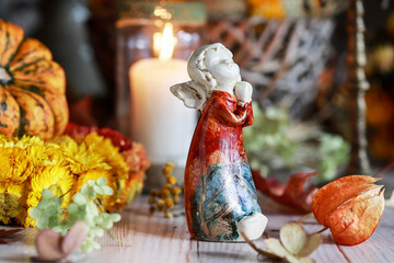 An autumn table decoration with an angel figure in the center, surrounded by many different plants.