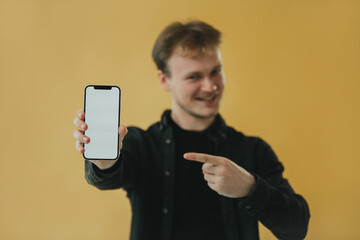 Man Showcasing a Smartphone Screen and Pointing With a Smile