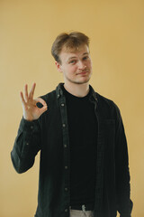 Confident Man Making an OK Gesture Against a Yellow Background