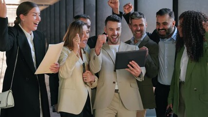 Group of young startup company businesspeople looking at tablet celebrating success achieving business goals
