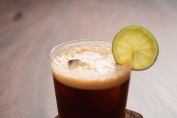 Espresso tonic in simple glass on walnut wood table with copy space