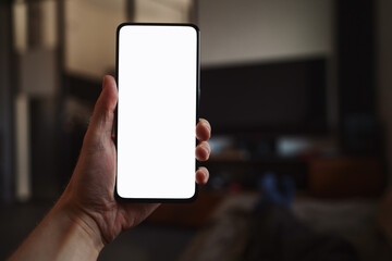Man hold smartphone with white screen in his hand lying on a couch in home environment