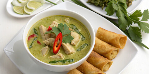  Authentic Thai green curry with fresh coriander, red chili, and crispy spring rolls – a flavorful and aromatic Asian delicacy