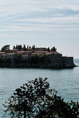 Obraz premium Sveti Stefan island in Budva town, Montenegro country. Luxury hotel is located in the middle of the Adriatic Sea. Houses with red tiled roofs. A popular place among tourists. View from the ground.