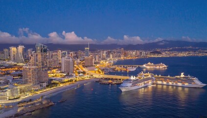 Naklejka premium City skyline at dusk with cruise ships, aerial view. Possible use for travel brochures, city guides, or tourism websites