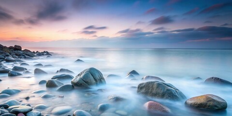 Obraz premium Serene Coastal Rocks at Dawn A Tranquil Seascape with Smooth Water and Hazy Sky