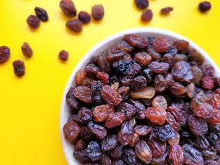 Dried pieces of delicious raisins on a yellow background.