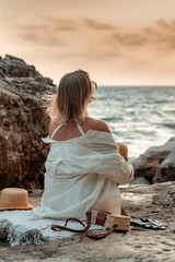 Woman Beach Relaxation - A woman in a white bikini and sunglasses sits on the beach with her legs crossed, looking out at the ocean.