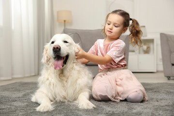 Little girl with cute dog on carpet at home