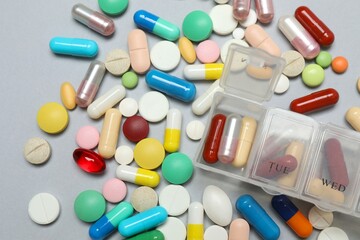 Plastic container with various pills on gray background