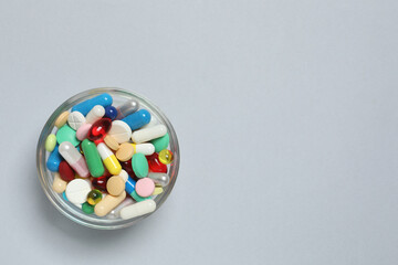 Various pills in a bowl on gray background