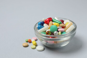 Various pills in a bowl on gray background