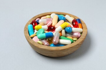 Various pills in a bowl on gray background
